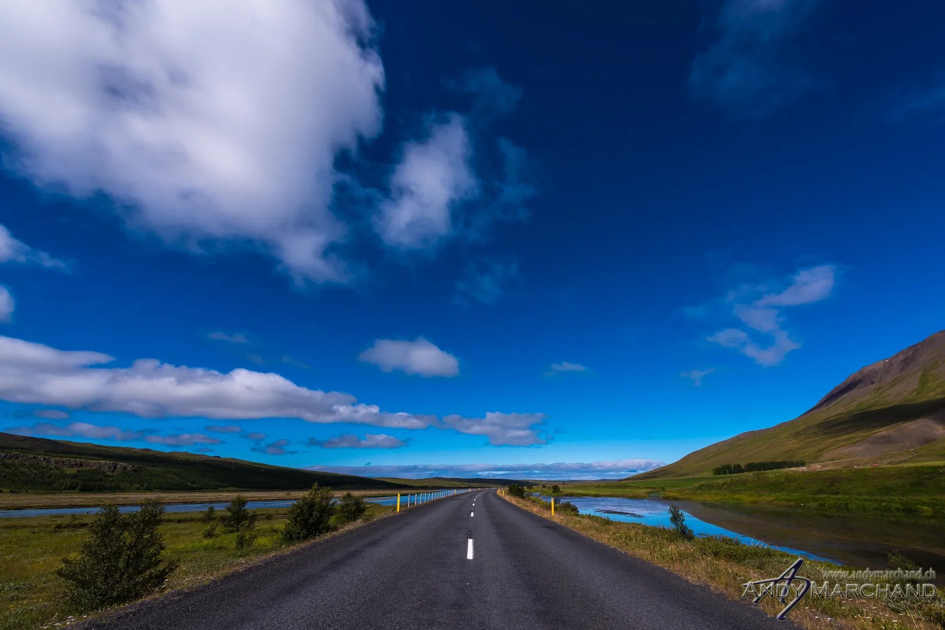 Leere Strasse durch eine weite isländische Landschaft