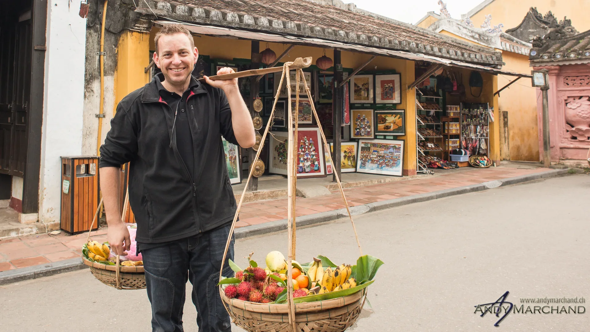 Andy Marchand trägt in Hoi An eine traditionelle Schulterstange mit Körben