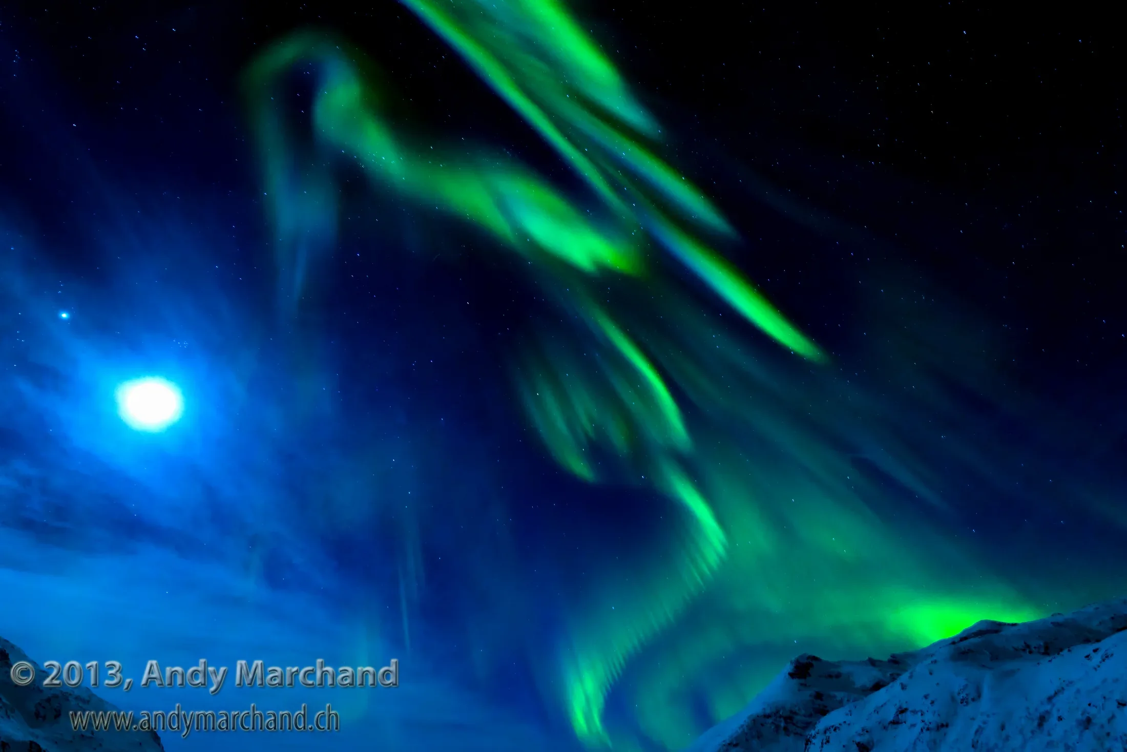 Grünes Nordlicht über verschneiten Bergen bei Tromsø